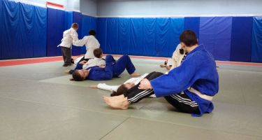 Combat de judo de 2 jeunes supervisé par un moniteur. Photo.