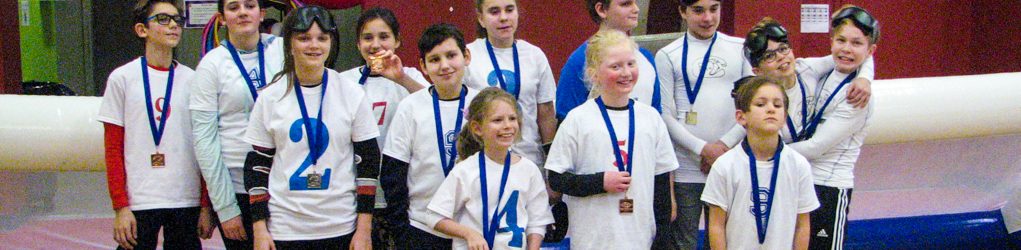 Photo de groupe. Les jeunes participants au tournoi souriants, avec leurs médailles. Les Phurax, les Griffons, les Dents de la mer et es Cougars.