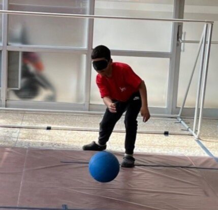 Photo d’un garçon, les yeux bandés, lançant un ballon de goalball.